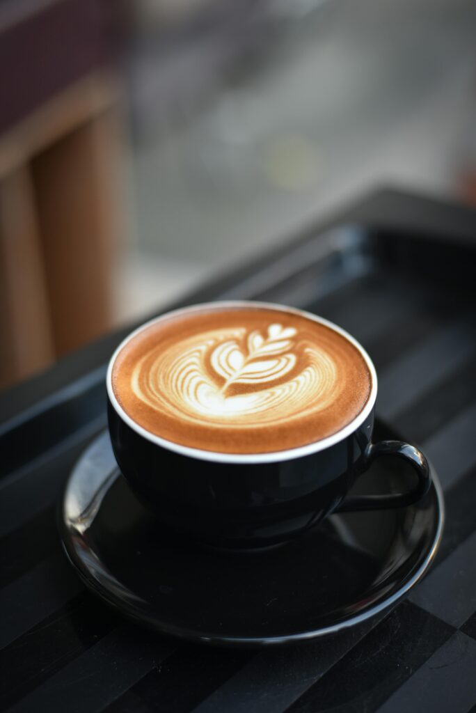 Black coffee cup on black saucer filled with coffee. 